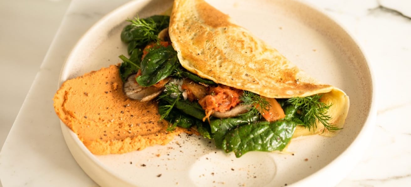 an omelette filled with fresh vegetables served on a plate with a garnish