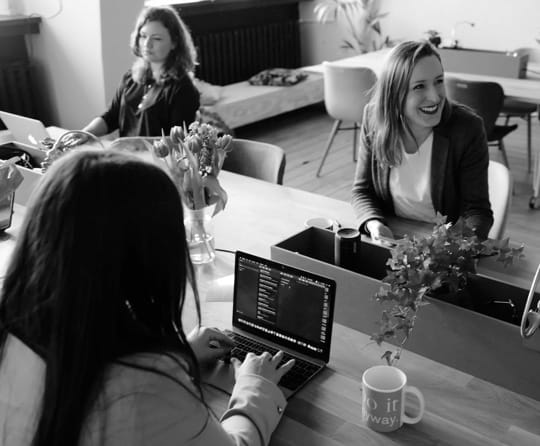 three women working at a desk in a coffee shop