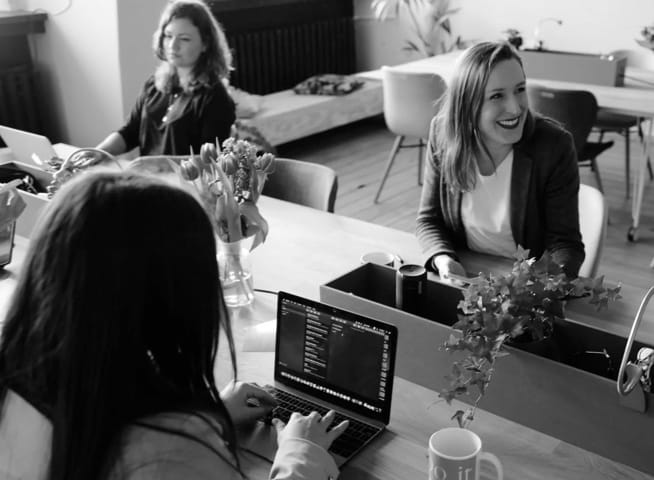 three women working at a desk in a coffee shop